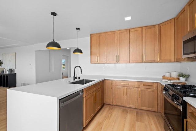 kitchen with stainless steel appliances, a peninsula, a sink, light wood-style floors, and light countertops