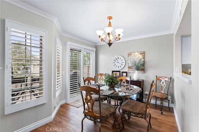 dining room with baseboards, ornamental molding, wood finished floors, and a notable chandelier