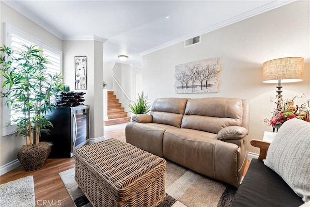 living room featuring baseboards, visible vents, ornamental molding, wood finished floors, and stairs