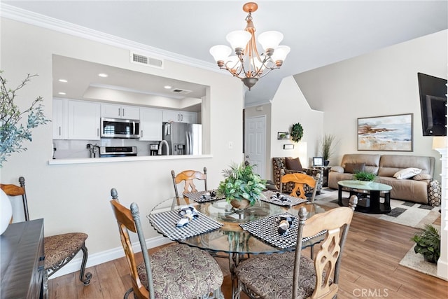 dining space with a chandelier, recessed lighting, visible vents, light wood-style floors, and crown molding