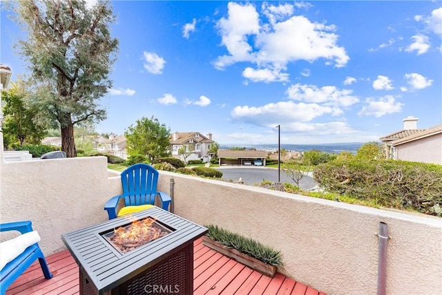 wooden deck featuring an outdoor fire pit and a residential view