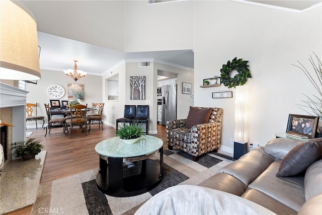 living room featuring ornamental molding, a notable chandelier, light wood-style flooring, and baseboards