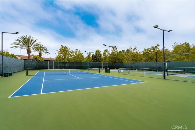 view of tennis court featuring community basketball court and fence