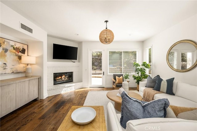 living room with dark wood-type flooring, visible vents, and a fireplace