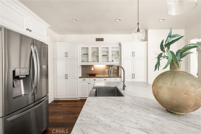 kitchen with visible vents, white cabinets, a sink, and stainless steel fridge with ice dispenser