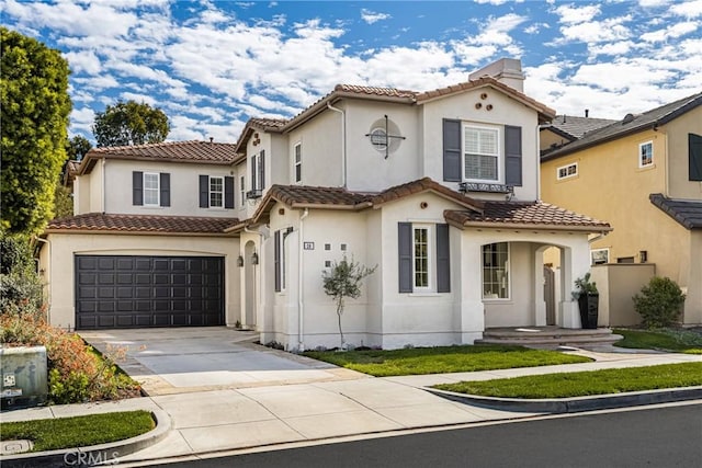 mediterranean / spanish house with a garage, a tile roof, concrete driveway, and stucco siding