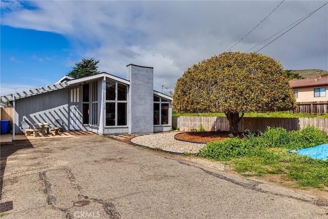 rear view of property with a chimney and fence