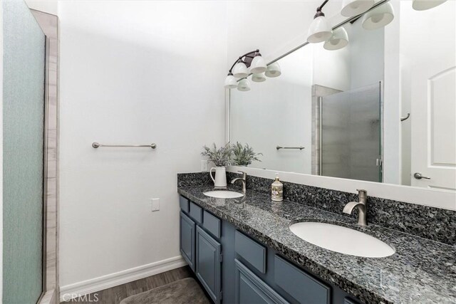 bathroom with a sink, a shower stall, baseboards, and wood finished floors