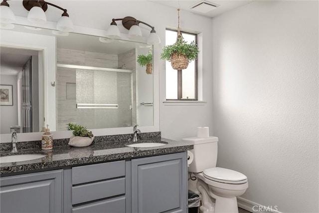 bathroom featuring toilet, double vanity, visible vents, and a sink