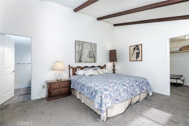 carpeted bedroom featuring vaulted ceiling with beams, a spacious closet, a closet, and baseboards