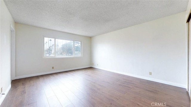 spare room with a textured ceiling, baseboards, and wood finished floors