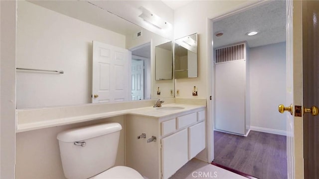 bathroom with visible vents, vanity, toilet, and wood finished floors