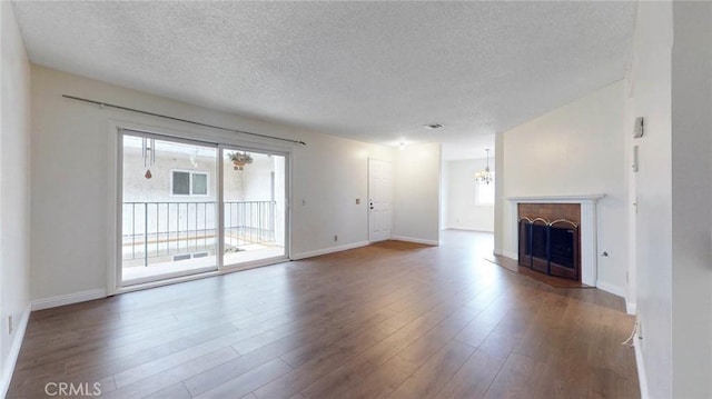 unfurnished living room with baseboards, wood finished floors, an inviting chandelier, a textured ceiling, and a fireplace