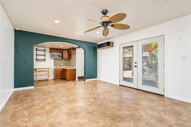 unfurnished living room with arched walkways, recessed lighting, french doors, and baseboards