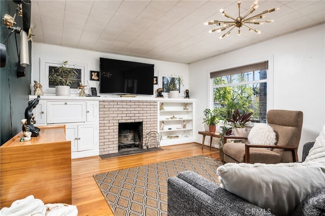 living room with an inviting chandelier, light wood-style flooring, and a fireplace