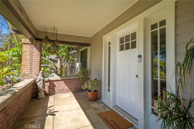 property entrance featuring brick siding and covered porch