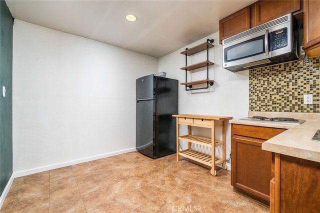 kitchen featuring baseboards, stainless steel appliances, light countertops, brown cabinets, and backsplash