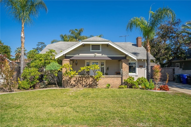 view of front of property with a front lawn, fence, brick siding, and a chimney