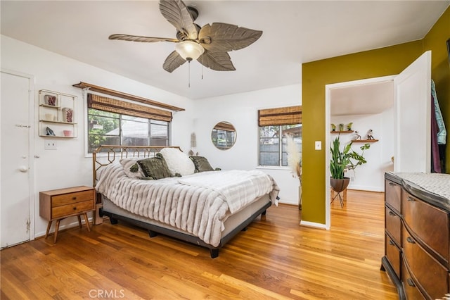 bedroom with multiple windows, baseboards, light wood-type flooring, and a ceiling fan