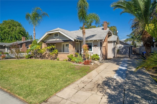 view of front of home featuring a gate, brick siding, a front lawn, and fence