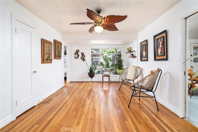 sitting room featuring light wood-style flooring, baseboards, and ceiling fan