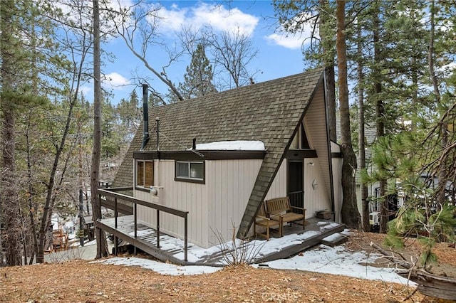 snow covered property with a shingled roof