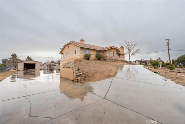 ranch-style home with an outbuilding, a chimney, and stucco siding