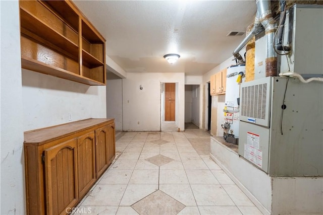 kitchen featuring light tile patterned floors, visible vents, brown cabinets, heating unit, and gas water heater