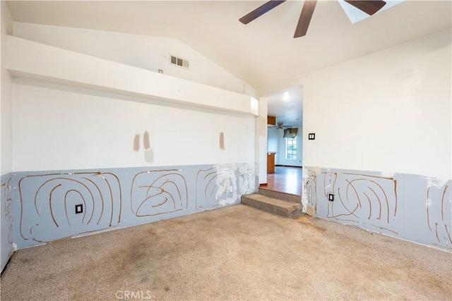 carpeted spare room featuring visible vents, vaulted ceiling, and ceiling fan