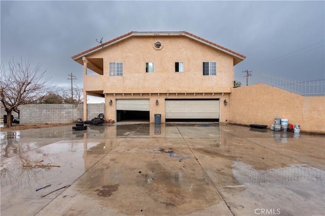 view of front facade with a garage, driveway, fence, and stucco siding