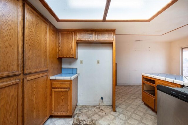 kitchen with tile countertops, light floors, baseboards, and brown cabinets