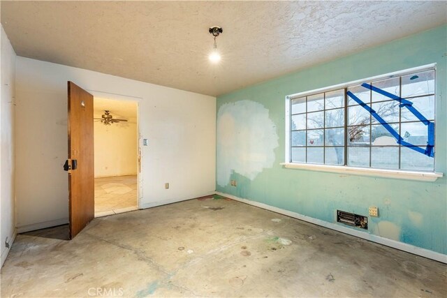 unfurnished room with a textured ceiling, baseboards, and unfinished concrete flooring