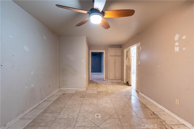 empty room featuring light tile patterned floors, ceiling fan, and baseboards