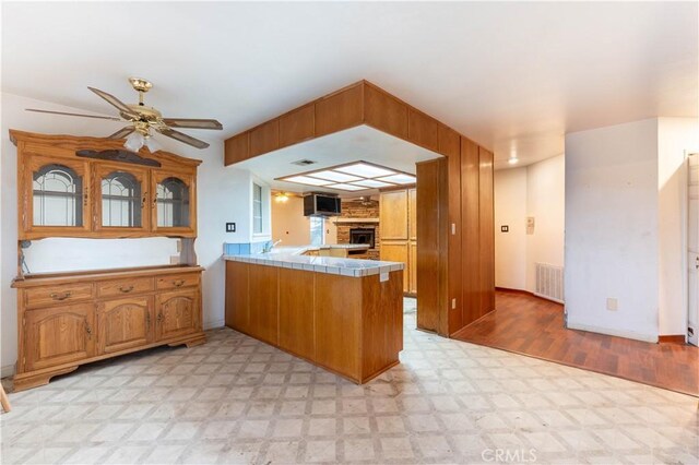 kitchen featuring a peninsula, stainless steel microwave, tile counters, and light floors