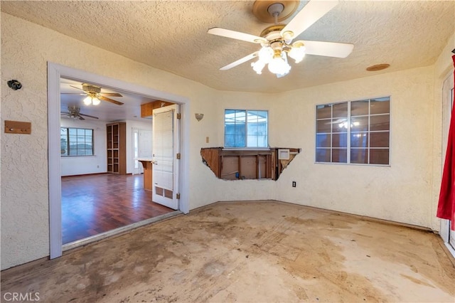 unfurnished room featuring a textured ceiling, a textured wall, ceiling fan, and a healthy amount of sunlight