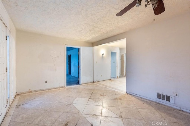 spare room with a textured ceiling, visible vents, and a ceiling fan