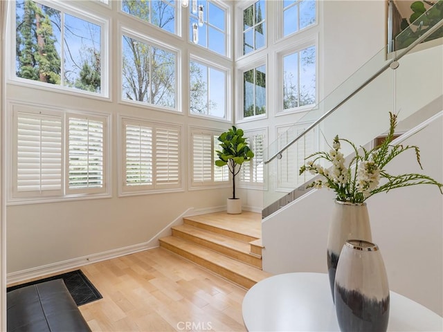 stairs featuring a high ceiling, baseboards, and wood finished floors