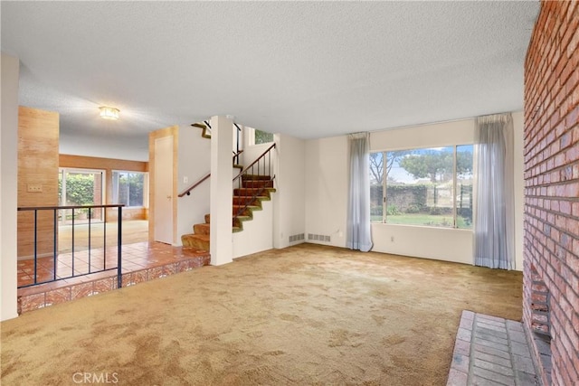 unfurnished living room featuring plenty of natural light, carpet, visible vents, and a textured ceiling