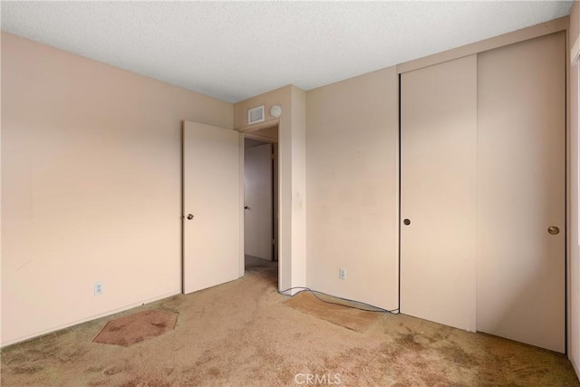 unfurnished bedroom with carpet, a closet, visible vents, and a textured ceiling