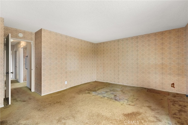 spare room with a textured ceiling, carpet, and wallpapered walls