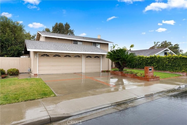 traditional home featuring a garage, a shingled roof, fence, and a front yard