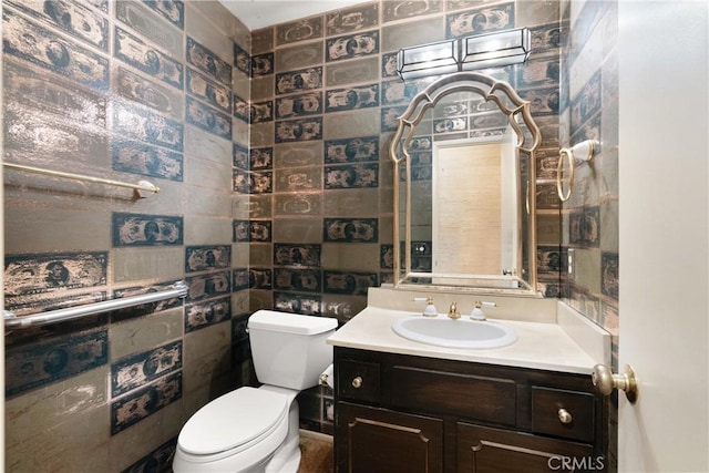 half bathroom featuring tile walls, vanity, and toilet