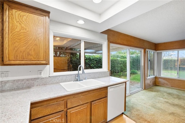 kitchen featuring a sink, brown cabinetry, light countertops, and dishwasher