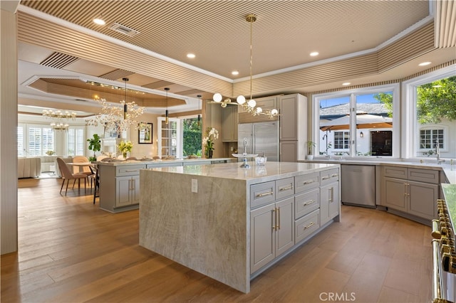 kitchen featuring appliances with stainless steel finishes, a kitchen island, a raised ceiling, and gray cabinetry