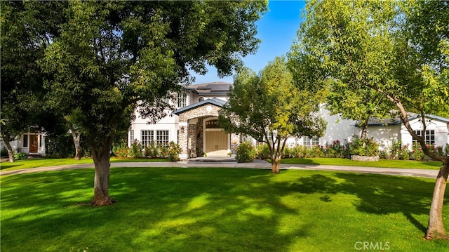 view of front of house featuring stone siding, solar panels, and a front yard