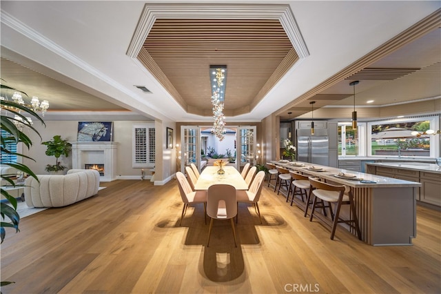 dining area featuring a chandelier, a tray ceiling, crown molding, and light wood finished floors