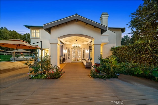 property entrance featuring french doors, a chimney, and stucco siding