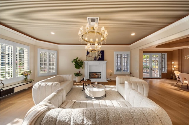 living room featuring a chandelier, a glass covered fireplace, visible vents, and crown molding