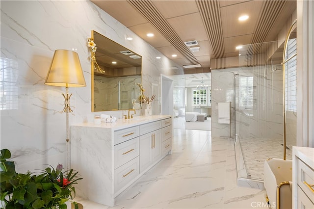 full bathroom featuring marble finish floor, vanity, a marble finish shower, and stone wall