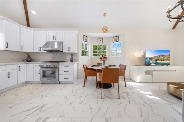 kitchen with marble finish floor, decorative backsplash, white cabinetry, high end stove, and under cabinet range hood